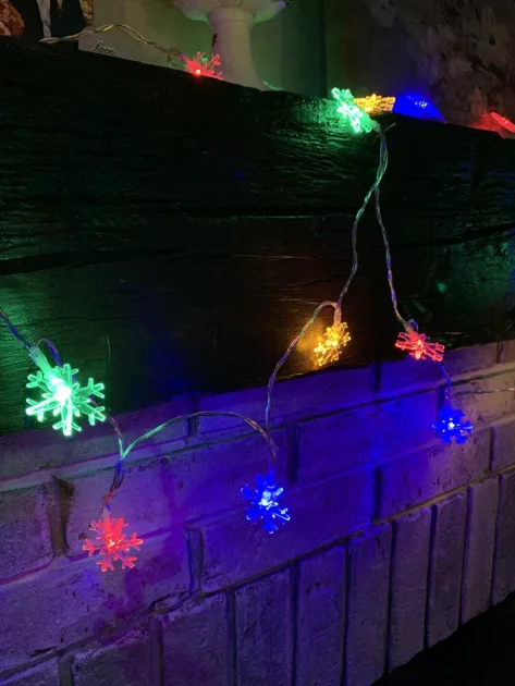Colorful Stringlights Closeup Side Angle View Wooden Cupboards Brick Snowflake Christmas Lights
